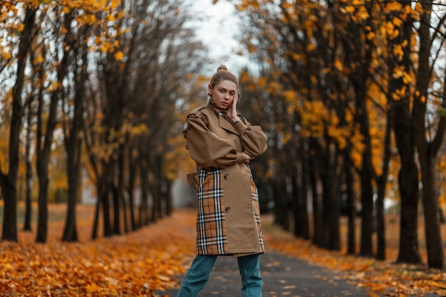 giovane donna con un taglio di capelli alla moda in un cappotto elegante pone all'aperto in un parco