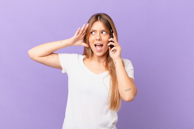 Giovane donna con un telefono cellulare che si sente felice, eccitata e sorpresa