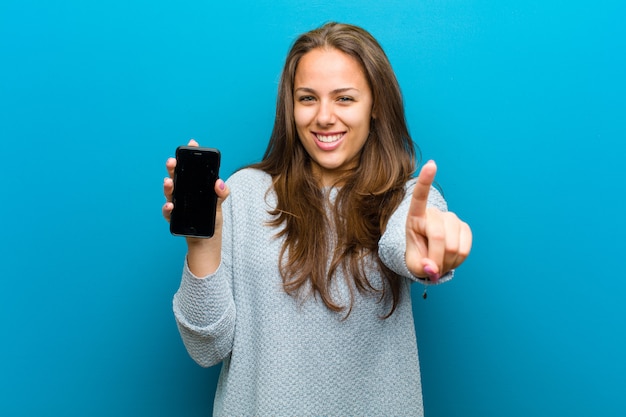 Giovane donna con un telefono cellulare sul blu