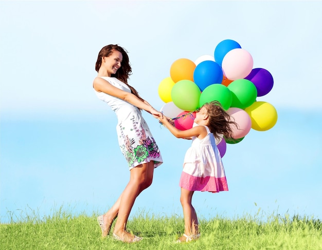 Giovane donna con una bambina carina e palloncini colorati