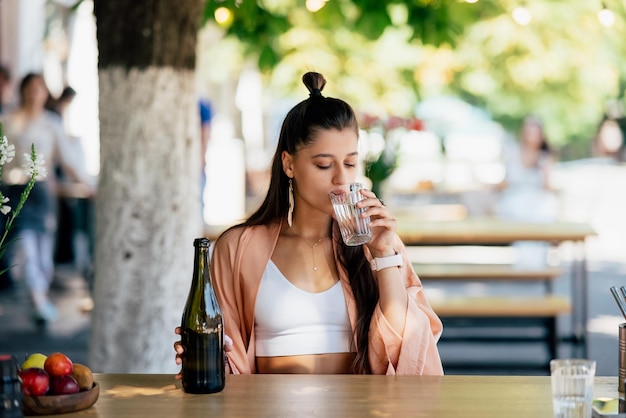 Giovane donna con una bibita fresca seduta in un caffè sulla strada