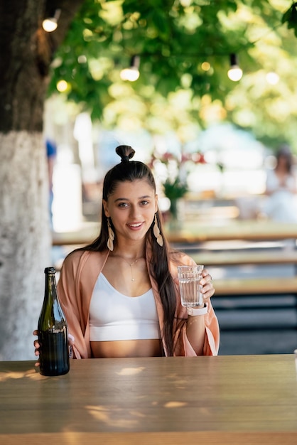 Giovane donna con una bibita fresca seduta in un caffè sulla strada