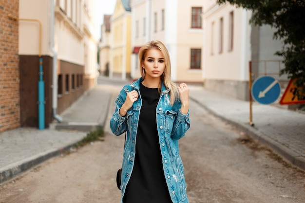 Giovane donna con una borsetta in jeans alla moda che cammina per strada