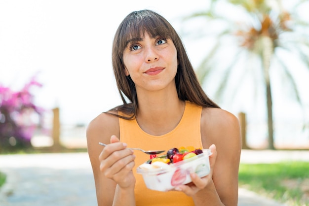 Giovane donna con una ciotola di frutta all'aperto