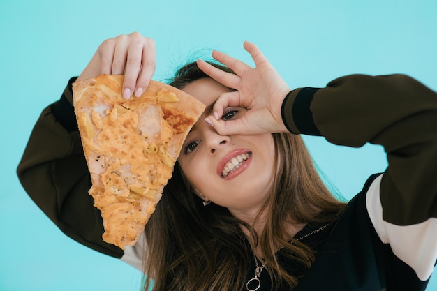 Giovane donna con una fetta di deliziosa pizza su sfondo colorato