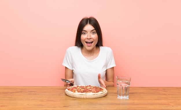 Giovane donna con una pizza in una tabella