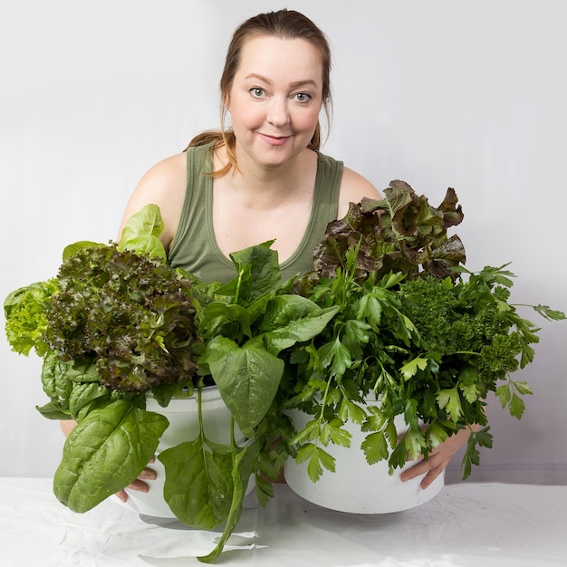 Giovane donna con una serie di ingredienti verdi lattuga spinaci per una dieta sana
