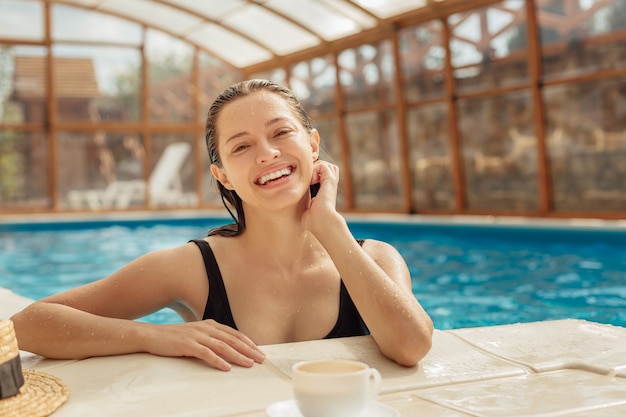 Giovane donna con una tazza di caffè in piscina