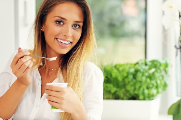 giovane donna con yogurt in cucina