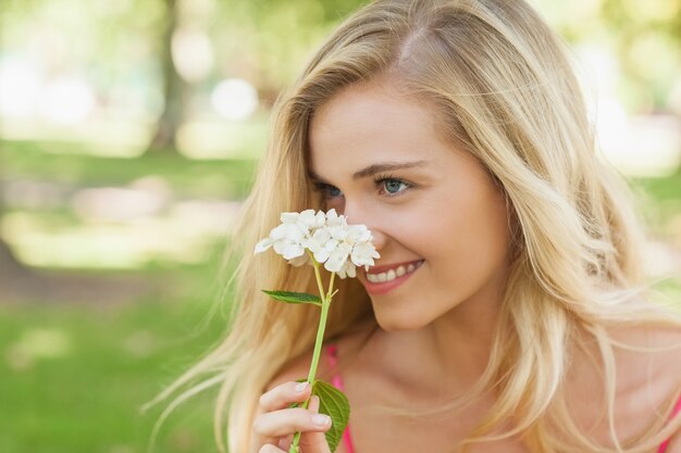 Giovane donna contenta che odora un fiore bianco