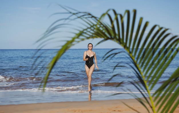 Giovane donna correre su una spiaggia paradiso tropicale spiaggia con sabbia bianca e palme concetto di turismo di viaggio