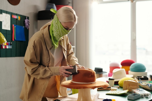 Giovane donna creativa con bandana sul cappello di feltro per lucidare il viso