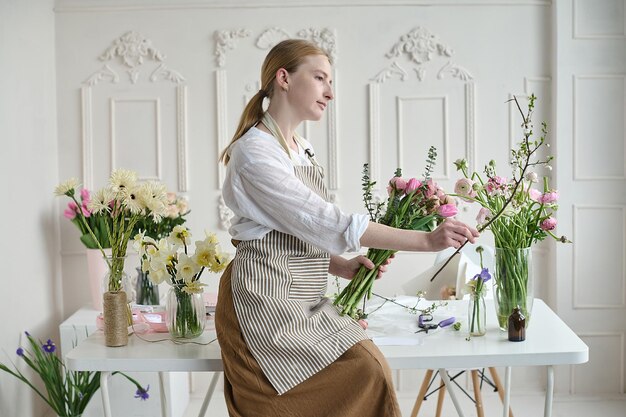 Giovane donna creativa in un negozio di fiori con un bouquet in mano Un avvio di attività di fiorista