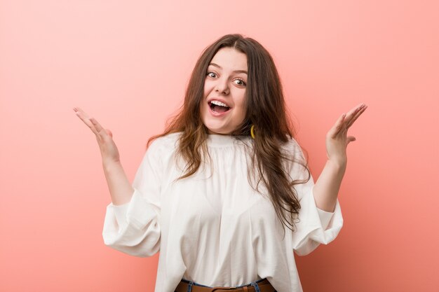 Giovane donna curvy caucasica che sta contro la parete rosa