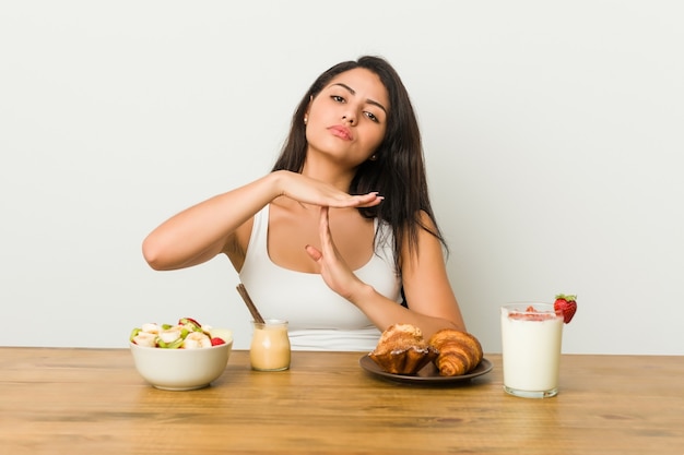 Giovane donna curvy che cattura una colazione che mostra un gesto di timeout.