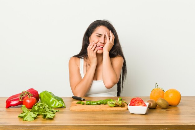 Giovane donna curvy che prepara un pasto sano piagnucolando e piangendo sconsolato.