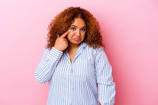 Giovane donna curvy latina isolata sul muro rosa piangendo, insoddisfatta di qualcosa