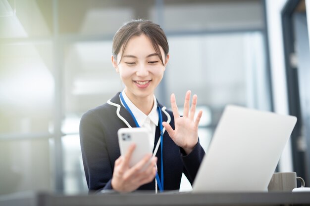 Giovane donna d'affari asiatica che parla con lo schermo del suo smartphone