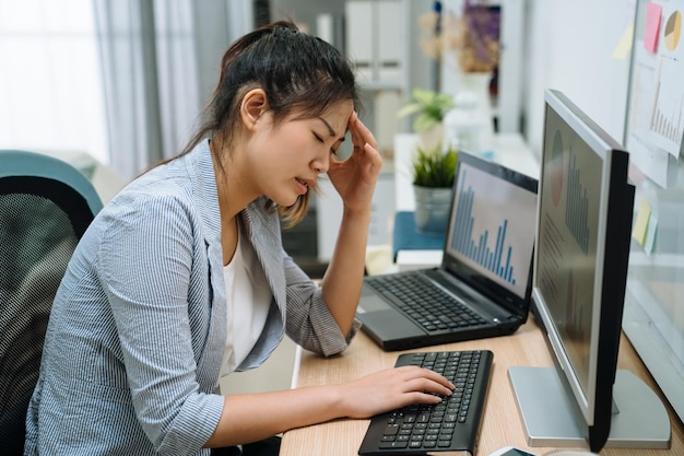 Giovane donna d'affari asiatica frustrata stressata che legge le notizie di Internet e-mail negative sul computer che si sente triste e stanca. lavoratrice freelance confusa sconvolta per un problema online durante il lavoro in ufficio a casa