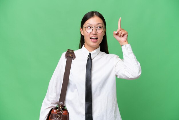 Giovane donna d'affari asiatica su sfondo isolato che intende realizzare la soluzione mentre si alza un dito