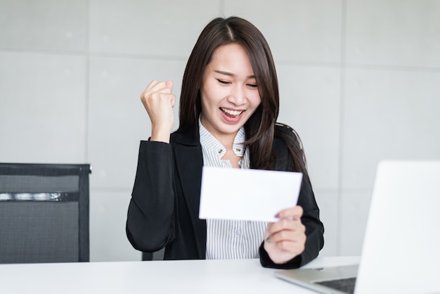 Giovane donna d'affari asiatici sentirsi felici dopo aver ricevuto denaro bonus o stipendio.