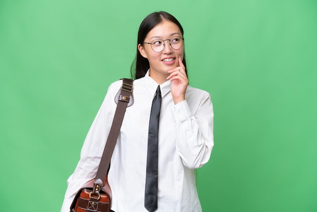 Giovane donna d'affari asiatici su sfondo isolato pensando un'idea mentre guardando in alto