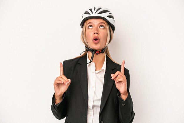 Giovane donna d'affari caucasica che indossa un casco da bici isolato su sfondo bianco rivolto verso l'alto con la bocca aperta.