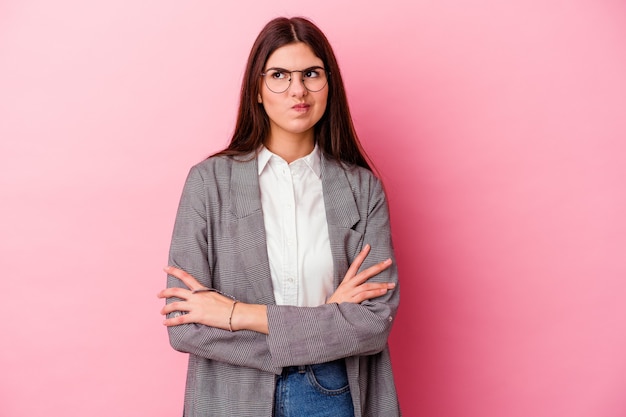 Giovane donna d'affari caucasica isolata su sfondo rosa infelice guardando a porte chiuse con espressione sarcastica.