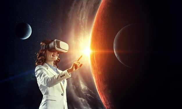 Giovane donna d'affari che indossa l'auricolare VR nello spazio. Tecnica mista
