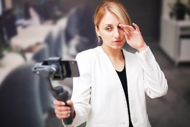 Giovane donna d'affari che registra video blog su smartphone nell'ufficio dell'azienda