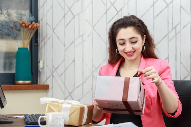 Giovane donna d'affari che ride e apre la sua confezione regalo Foto di alta qualità