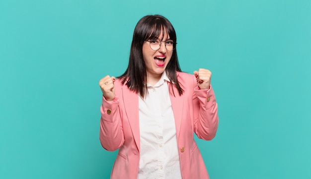 Giovane donna d'affari che si sente felice, sorpresa e orgogliosa, che grida e celebra il successo con un grande sorriso