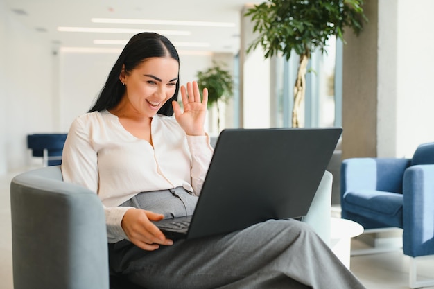 Giovane donna d'affari con laptop seduto nella hall del business center