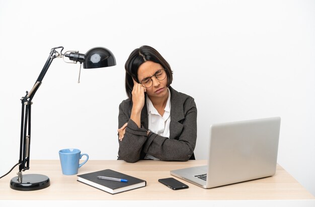 Giovane donna d'affari di razza mista che lavora in ufficio con mal di testa