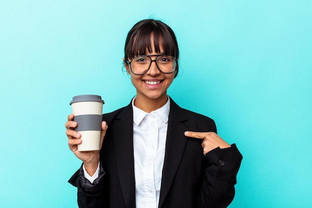 Giovane donna d'affari di razza mista che tiene un caffè isolato su sfondo blu persona che punta a mano a uno spazio copia maglietta, orgoglioso e fiducioso