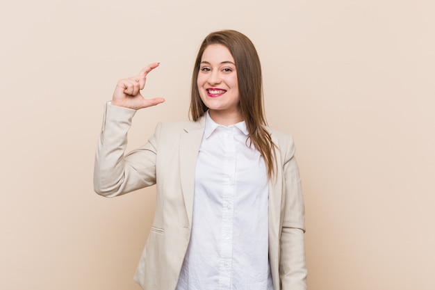 Giovane donna d'affari in possesso di qualcosa di piccolo con gli indici, sorridente e fiducioso.