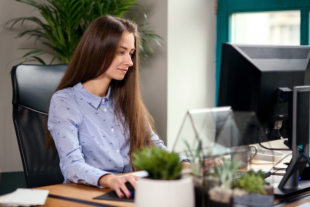 Giovane donna d'affari, lavorando al computer in ufficio moderno.