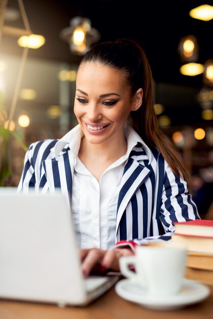 Giovane donna d'affari, lavorando su un computer portatile al bar caffetteria.