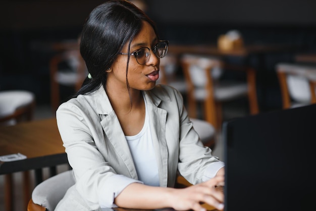 Giovane donna d'affari o studente afroamericana concentrata che guarda al computer portatile, donna di colore seria che lavora o studia con il computer facendo ricerche o preparandosi per l'esame online