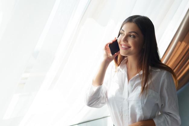 Giovane donna d'affari, parlando con il telefono in hotel.