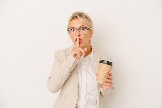 Giovane donna d'affari russa che tiene caffè da asporto isolato su sfondo bianco mantenendo un segreto o chiedendo silenzio.