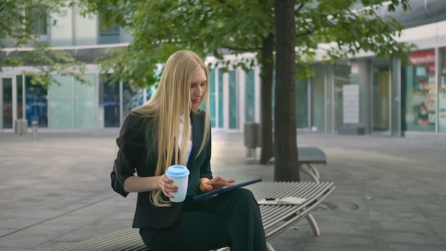 Giovane donna d'affari utilizzando la tavoletta e bere caffè.