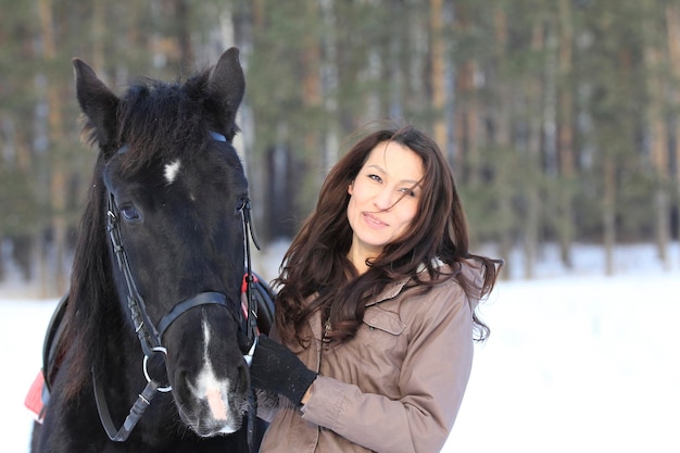 Giovane donna dai capelli neri che abbraccia un cavallo - ritratto, primo piano