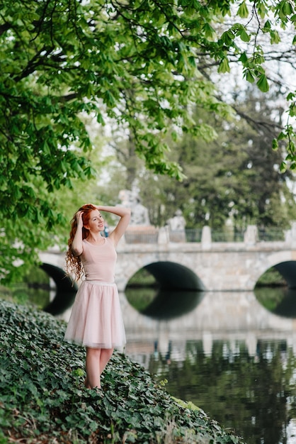 Giovane donna dai capelli rossi che cammina in un parco con una grande villa bianca