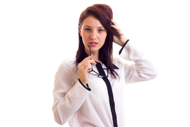 Giovane donna dall'aspetto elegante in camicia bianca e nera e con i capelli scuri su sfondo bianco in studio