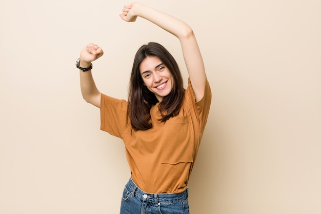 Giovane donna del brunette contro una priorità bassa beige che celebra un giorno speciale