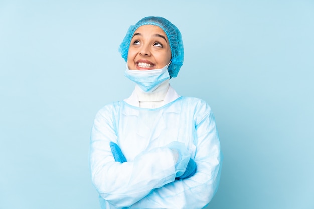 Giovane donna del chirurgo in uniforme blu che osserva in su mentre sorridendo