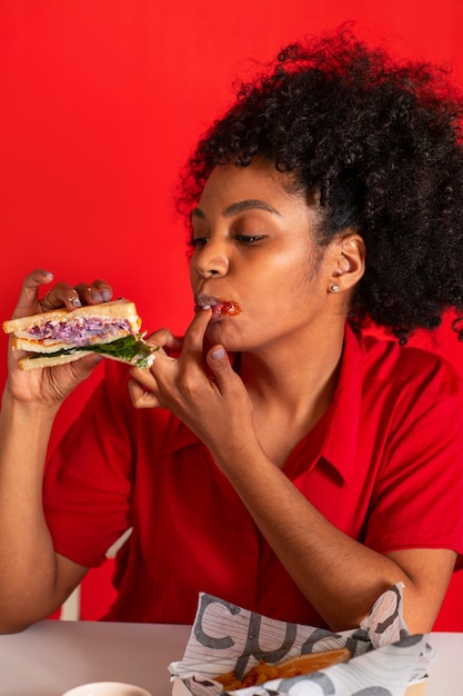 Giovane donna del colpo medio che mangia panino