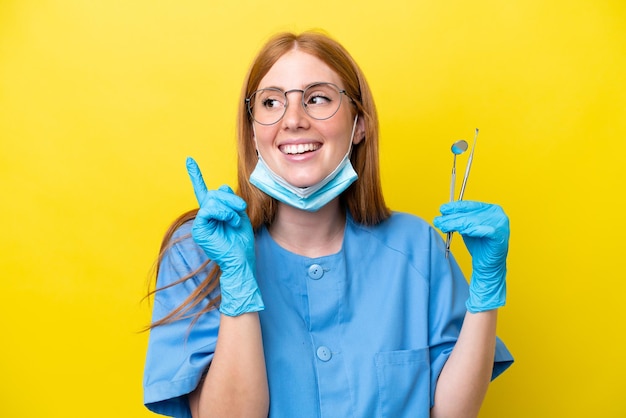 Giovane donna del dentista rossa isolata su sfondo giallo che indica una grande idea