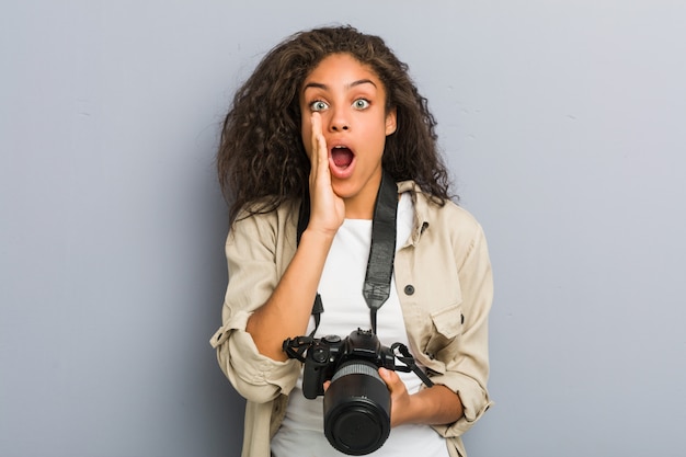 Giovane donna del fotografo che tiene un gridare della macchina fotografica eccitato alla parte anteriore